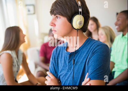 Teenage boy listening to headphones at party Banque D'Images