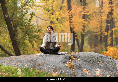 Asian woman sitting on rock in park Banque D'Images