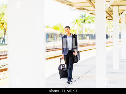 Black businessman rolling assurance on train platform Banque D'Images