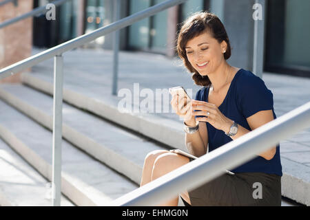 Caucasian businesswoman using cell phone on staircase Banque D'Images