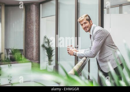 Caucasian businessman drinking coffee sur balcon bureau Banque D'Images