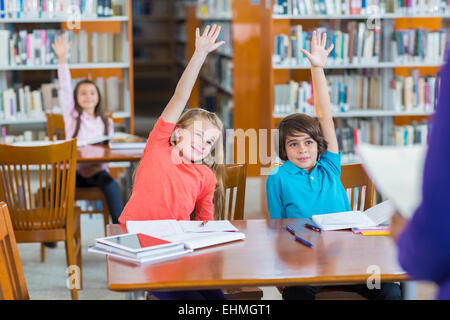 Les élèves lèvent la main dans la bibliothèque Banque D'Images