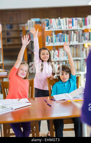 Les élèves lèvent la main dans la bibliothèque Banque D'Images