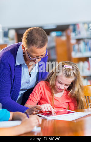 Aider les enseignants étudiants digital tablet in library Banque D'Images