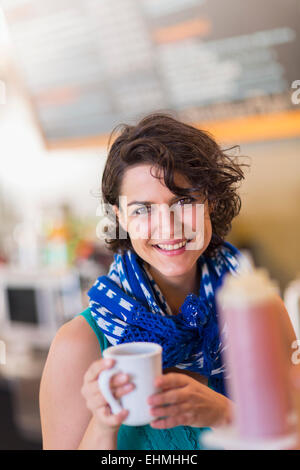 Mixed Race woman holding cup of coffee in cafe Banque D'Images