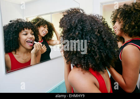 Les femmes de race mixte miroir en appliquant le maquillage Banque D'Images