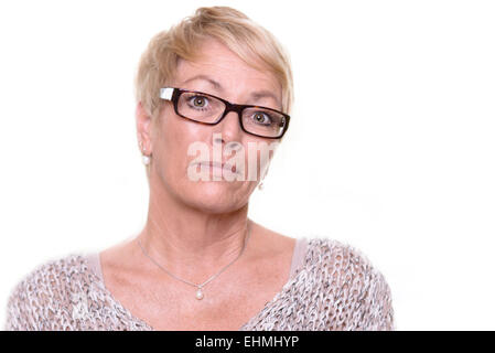 Méfiant stern femme d'âge moyen portant des lunettes avec une grave expression inflexible à attentivement à l'appareil photo, la tête d'une Banque D'Images