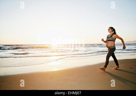 Pregnant Hispanic woman walking on beach Banque D'Images