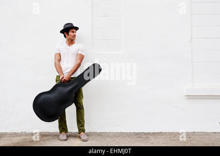 Mixed Race musicien exerçant son étui à guitare Banque D'Images