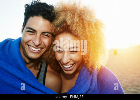 Hispanic couple wrapped in blanket on beach Banque D'Images