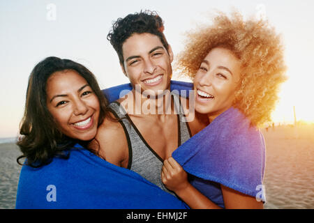 Amis hispaniques enveloppée de couverture sur beach Banque D'Images