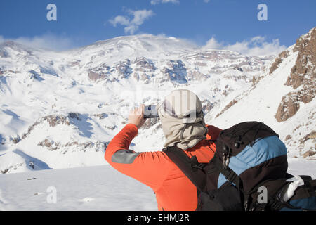 Randonneur hispaniques taking photograph of snowy mountain range Banque D'Images