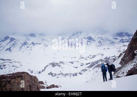 Les randonneurs hispanique en admirant les montagnes pittoresques de neige Banque D'Images