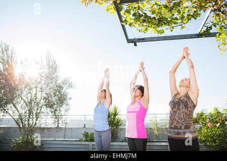 Les femmes pratiquant le yoga ensemble on urban rooftop Banque D'Images