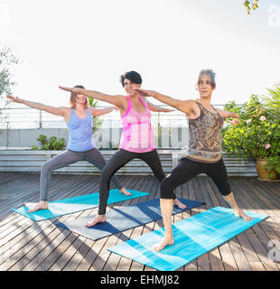 Les femmes pratiquant le yoga ensemble on urban rooftop Banque D'Images