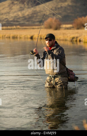 Fisherman casting in river Banque D'Images