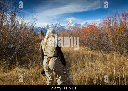 Older Caucasian woman carrying fishing supplies in field Banque D'Images