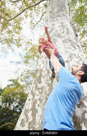 Woman lifting baby son under tree Banque D'Images