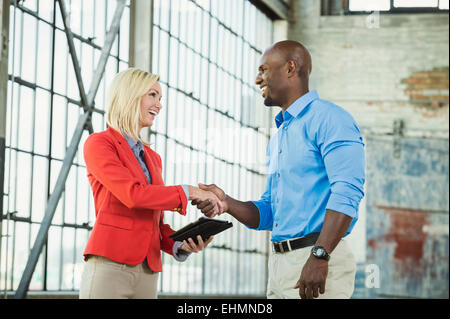 Business people shaking hands in warehouse Banque D'Images