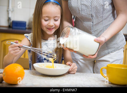 Petite fille de battre la pâte pour crêpes Banque D'Images