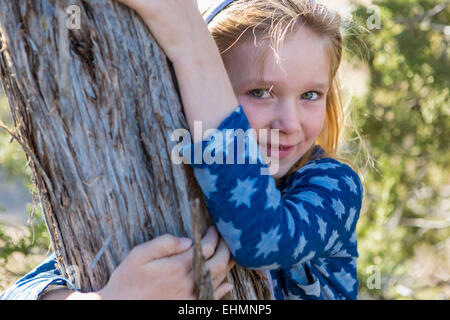 Caucasian girl hugging tree outdoors Banque D'Images