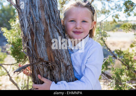 Smiling girl hugging tree Banque D'Images