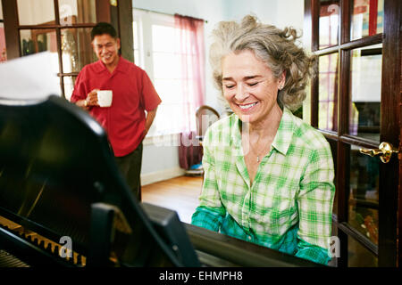 Homme Femme regarder jouer du piano dans la salle de séjour Banque D'Images