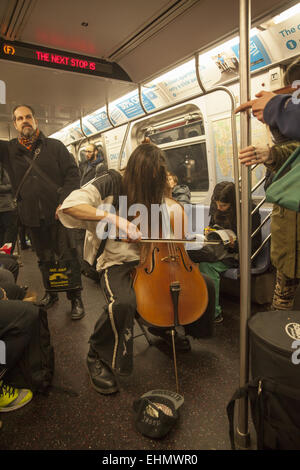 Le violoncelliste classique joue pour obtenir des conseils sur une voiture de métro de Manhattan, New York. Banque D'Images