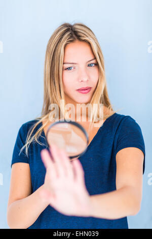 Femme à l'aide d'une loupe pour examiner sa main. Banque D'Images