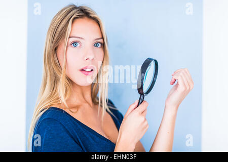 Femme à l'aide d'une loupe pour examiner sa main. Banque D'Images