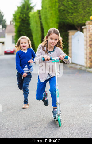 Les enfants sur les scooters à l'extérieur. Banque D'Images