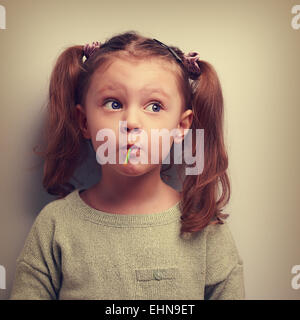 Fun girl eating candy avec surprenant de penser de grands yeux. Vintage closeup portrait Banque D'Images