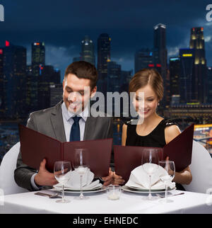 Smiling couple avec des menus au restaurant Banque D'Images