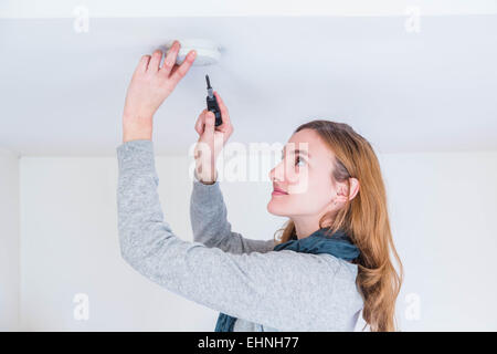 Femme de l'installation d'un détecteur de fumée. Banque D'Images