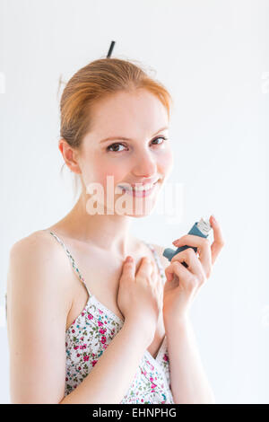 Femme à l'aide d'un inhalateur bronchodilatateur en aérosol contenant pour le traitement de l'asthme. Banque D'Images