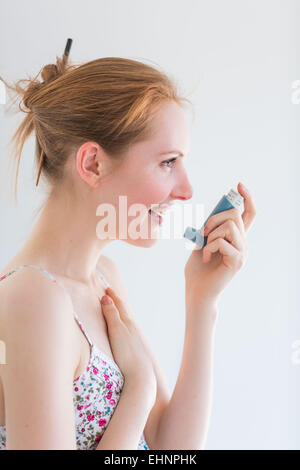Femme à l'aide d'un inhalateur bronchodilatateur en aérosol contenant pour le traitement de l'asthme. Banque D'Images