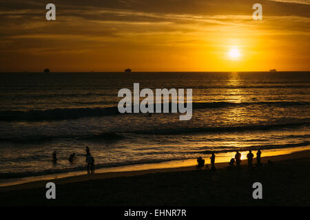 Les gens sur la plage et coucher de soleil sur l'océan Pacifique à Huntington Beach, en Californie. Banque D'Images