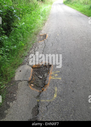 Poule dans broken tarmac pays route marquée d'avertir les cyclistes du danger, Berkshire, Juillet Banque D'Images