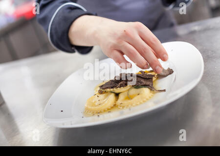 Caillebotis Chef de champignons truffes de chauffage sur raviolis faits maison dans un restaurant de cuisine tout en préparant le dîner, une vue rapprochée de Banque D'Images