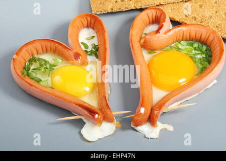 Deux saucisses dans un plat en forme de cœur. Banque D'Images