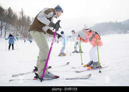 Les jeunes parents d'apprendre aux enfants à skier Banque D'Images