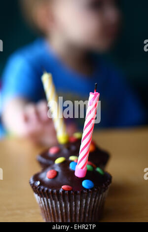 Jeune garçon et birthday cupcake avec bougies soufflées Banque D'Images