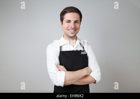 Shop assistant avec un tablier (supermarché, café-bar) sur fond gris Banque D'Images