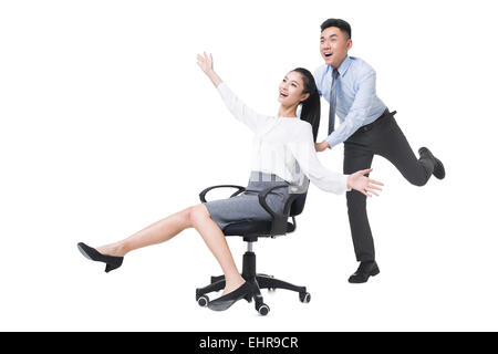 Businessman pushing woman chaise de bureau Matériel roulant Banque D'Images