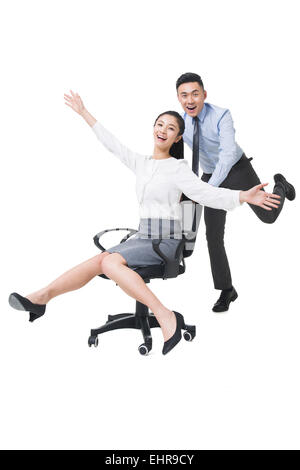 Businessman pushing woman chaise de bureau Matériel roulant Banque D'Images