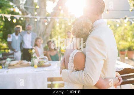 Young couple embracing in jardin lors de votre réception de mariage Banque D'Images