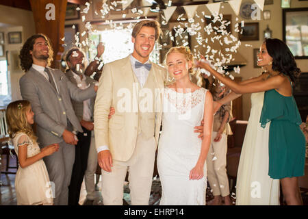 Portrait of smiling young couple standing in relevant des confettis pendant votre réception de mariage Banque D'Images