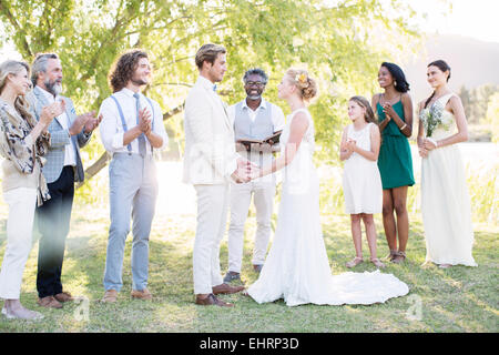 Jeune couple et invités pendant la cérémonie du mariage dans le jardin intérieur Banque D'Images