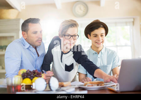 Adolescents avec le père à l'aide d'ordinateur portable dans la salle à manger Banque D'Images