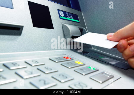 Homme d'affaires main insère une carte de crédit dans le distributeur et retire de l'argent Banque D'Images